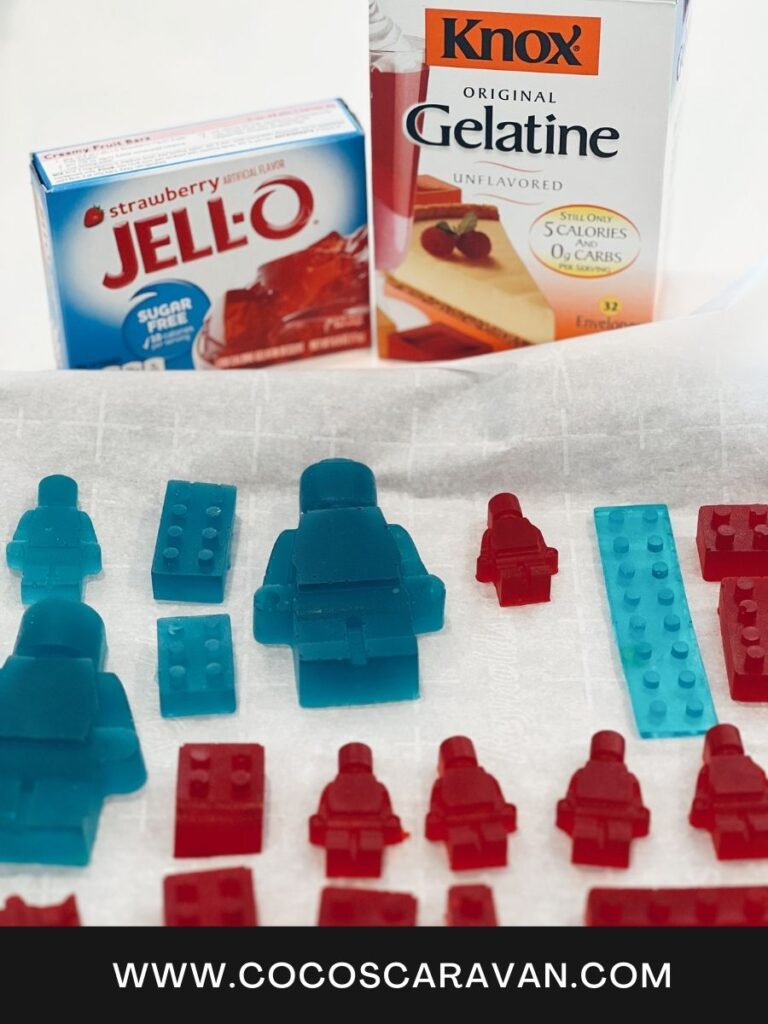 A colorful assortment of homemade LEGO gummies arranged neatly on a white plate, showcasing the vibrant hues of red, yellow, green, and blue. Each gummy is shaped like the iconic LEGO bricks, with intricate details and a glossy finish. The background features various LEGO pieces scattered around, adding to the playful and creative atmosphere of the scene.